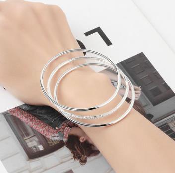 Trois bracelets plaqués argent sont portés en même temps